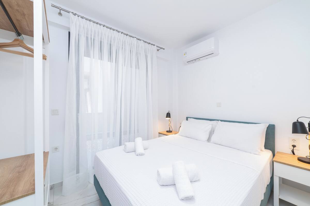 Une chambre d’hôtel moderne avec un grand lit, une table de chevet avec une lampe et une armoire.