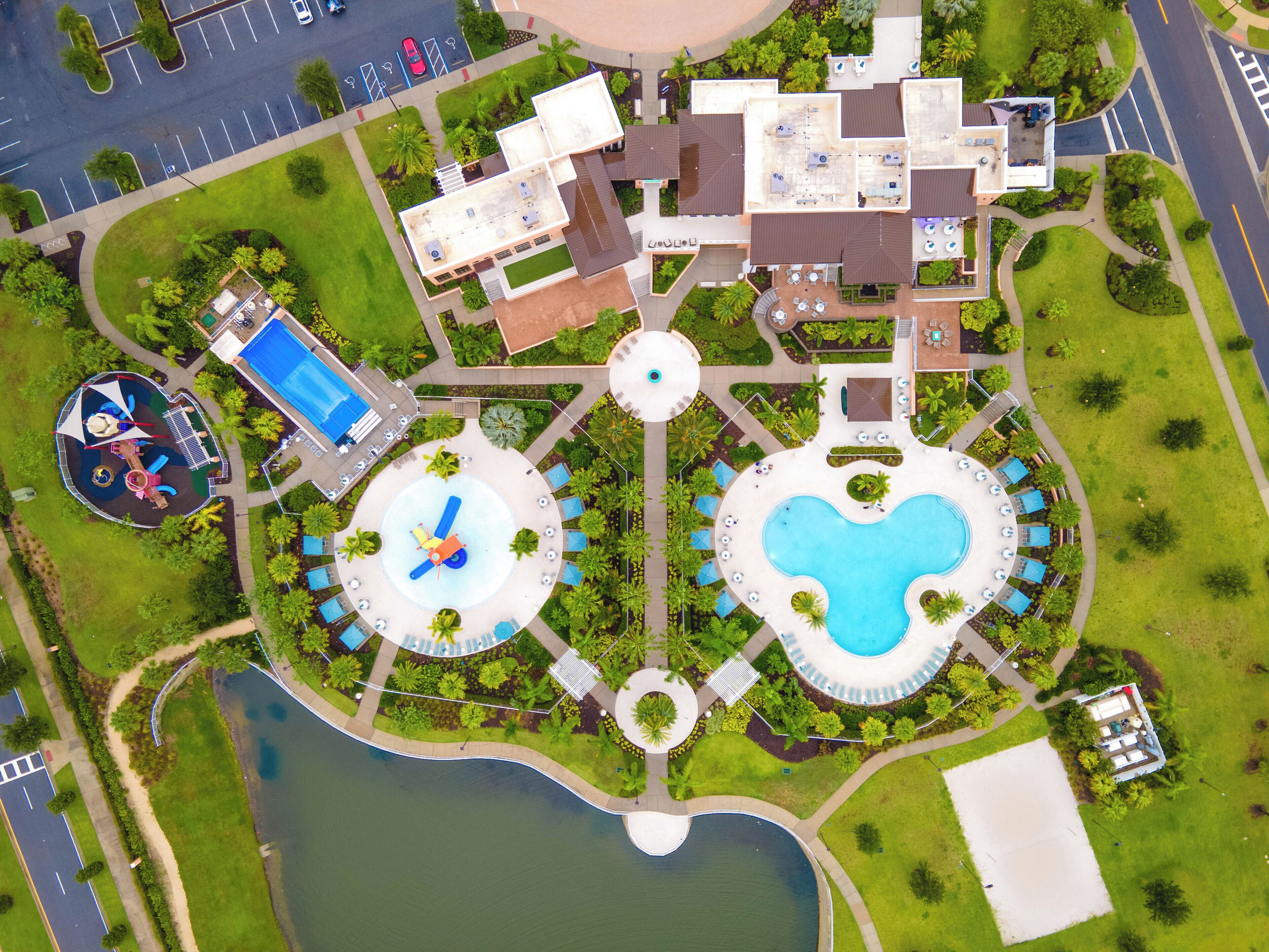 An aerial view of a resort with a central pool, multiple guest rooms, and a children's play area.