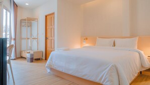 A hotel room with a large bed, a wooden wardrobe, a chair, and a small table. - Baan Cocoa Boutique Hotel (Takua Thung)