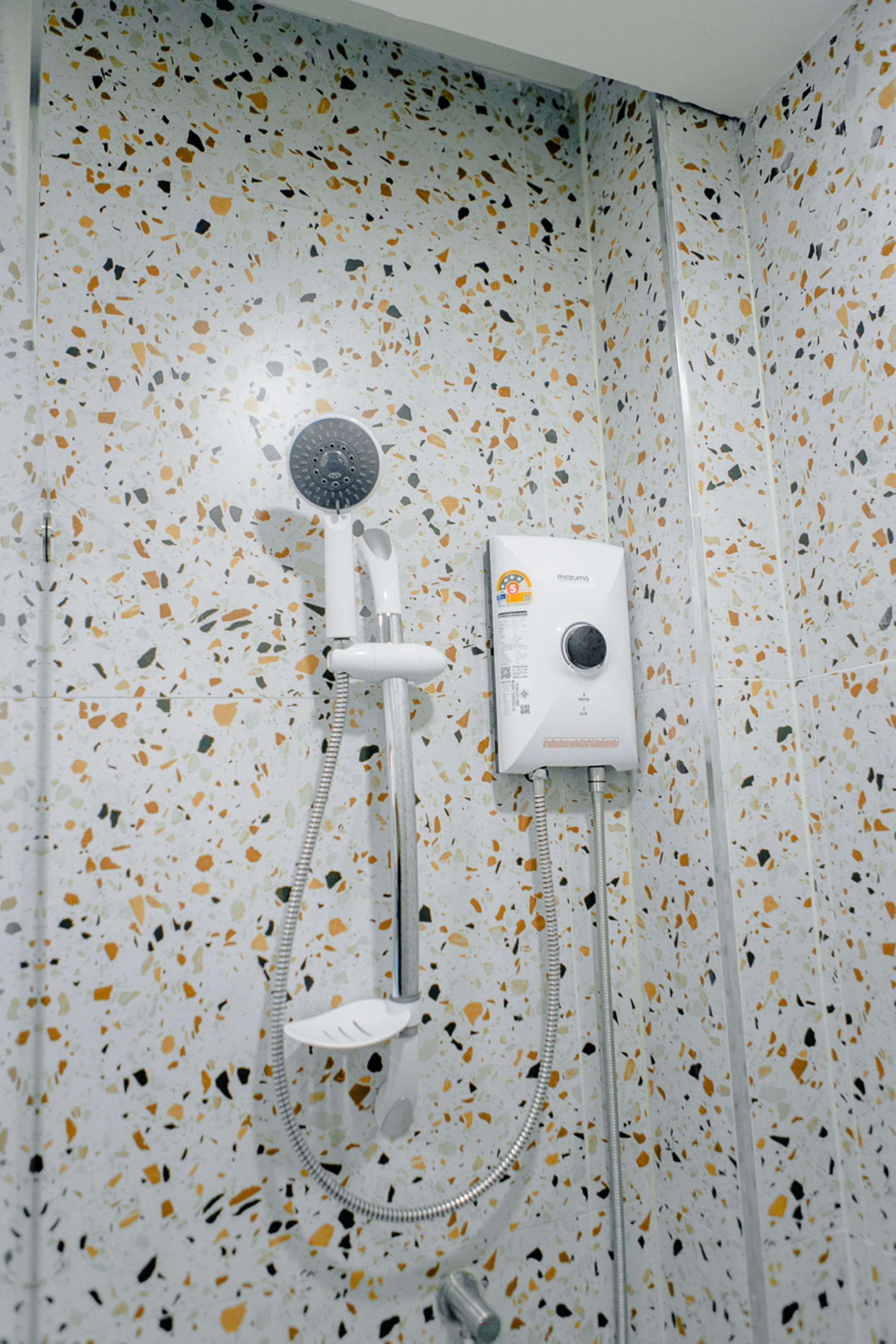 A shower with a handheld showerhead and a wall-mounted control panel.