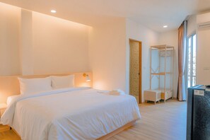 Una habitación de hotel con una cama grande, mesitas de noche, un armario y un escritorio.