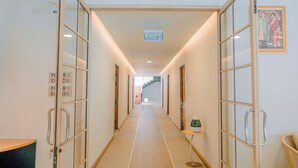 A hotel hallway with an exit sign, a staircase at the end, and a framed picture on the wall. - Baan Cocoa Boutique Hotel (Takua Thung)