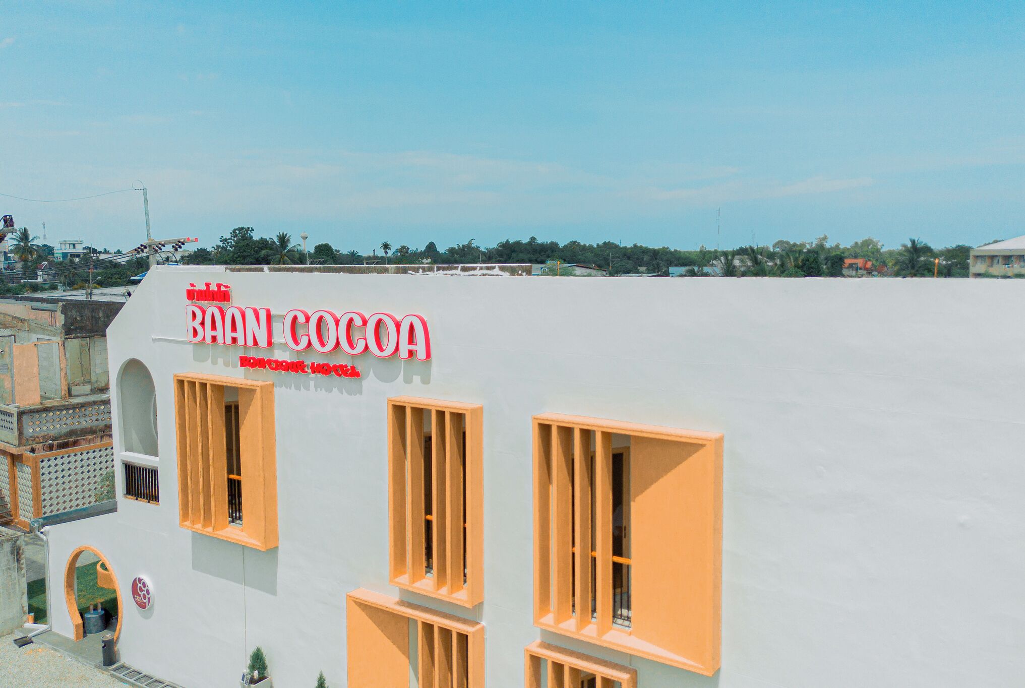 A building with a sign reading "BAAN COCOA" and a clear sky in the background.