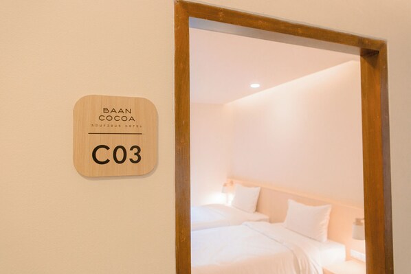 Una habitación de hotel con un letrero de madera en la pared que dice "BAAN COCOA C03".