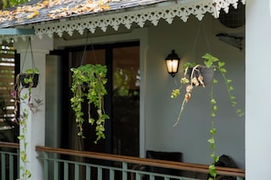 A porch with hanging planters and a white railing. - Villa Anjuna By Akama Stays (Anjuna)