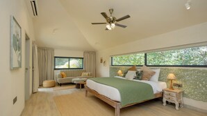 Un dormitorio con cama, sofá, ventana y ventilador de techo.