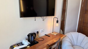 Una stanza piccola e accogliente con un tavolo di legno, una sedia, una televisione a parete e una lampada.