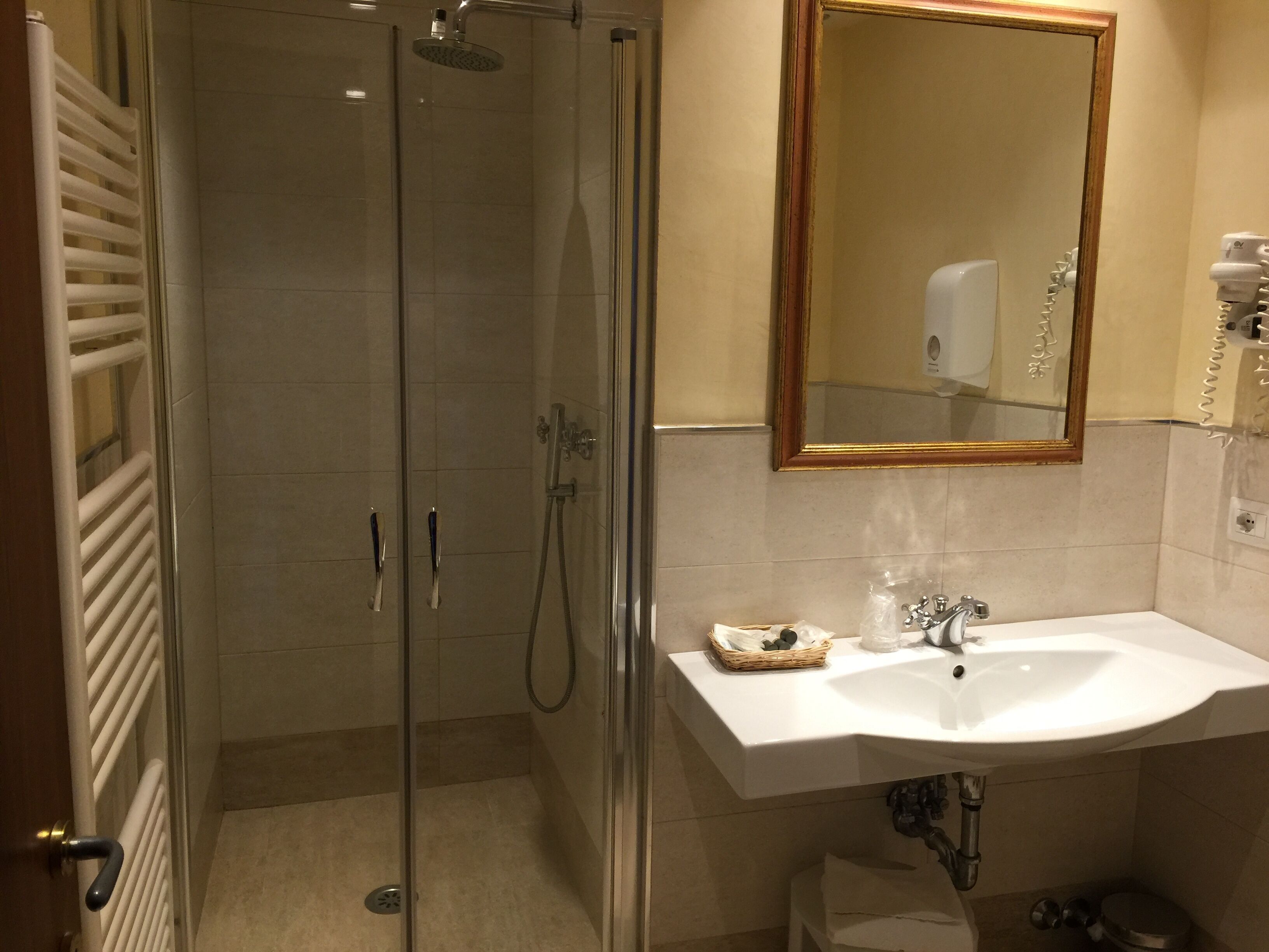 A modern bathroom with a glass-enclosed shower, a white sink, and a mirror above it.