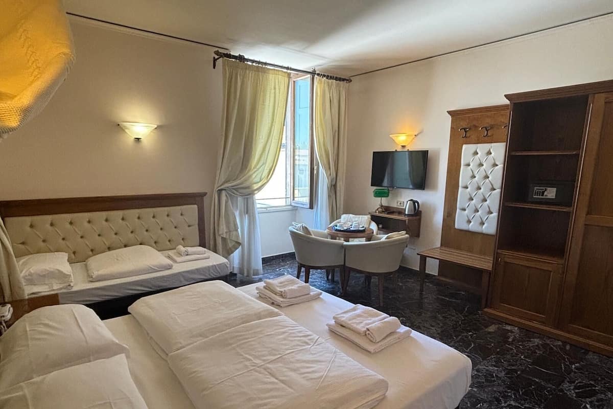 A hotel room with two beds, a desk, a TV, and a wardrobe.