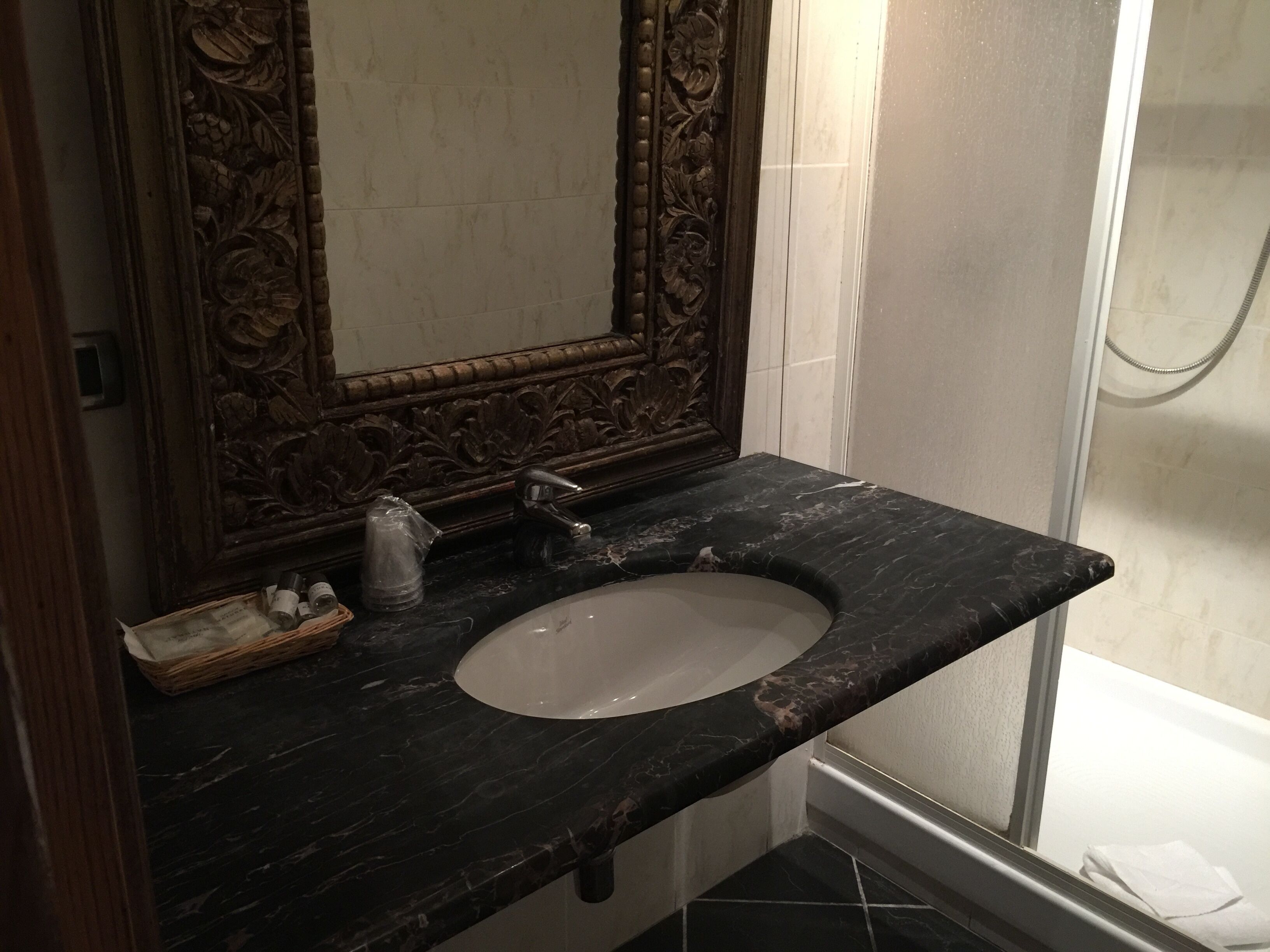 A bathroom with a marble sink, wooden vanity, and a shower.