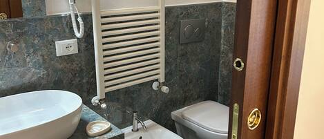 Un baño con bañera, bidé, inodoro y un perchero para toallas.