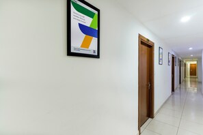 A hallway with doors numbered 201 to 210, a framed poster on the wall, and a tiled floor. - Treebo Anand The Mall Solan (Solan)