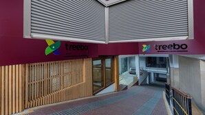 A modern interior with closed shutters, a wooden slatted wall, and a staircase leading to an upper level. - Treebo Anand The Mall Solan (Solan)
