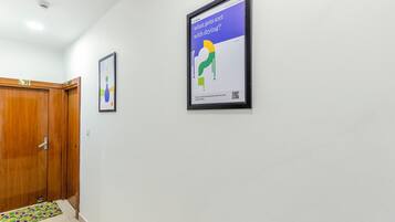 Un pasillo con una puerta de madera, un felpudo colorido y un cartel en la pared.