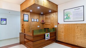 A wooden reception desk with a 'treebo' sign, framed informational posters, and a bulletin board. - Treebo Anand The Mall Solan (Solan)