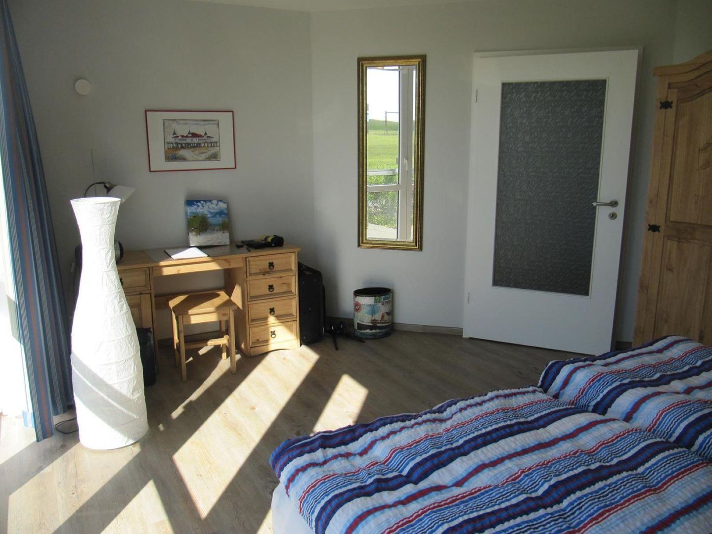 A bedroom with a bed, a desk, a chair, a window, and a door.