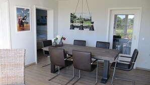 A dining area with a wooden table, six chairs, and a hanging pendant light. - Seeadler LH-105 - Comfortable vacation apartment with 2 terraces (Stolpe auf Usedom)