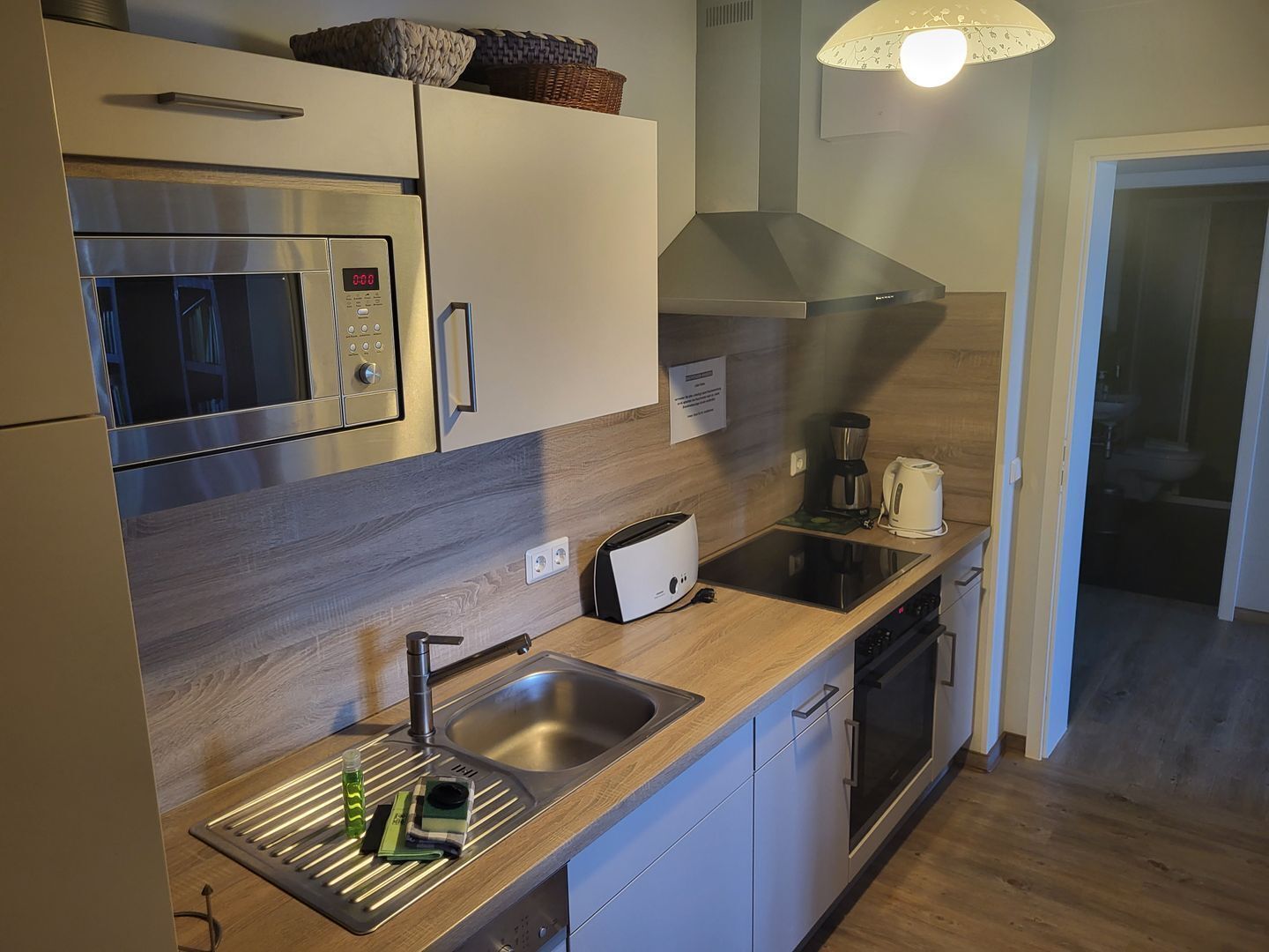 A modern kitchen with a stainless steel microwave, a built-in oven, and a coffee maker.
