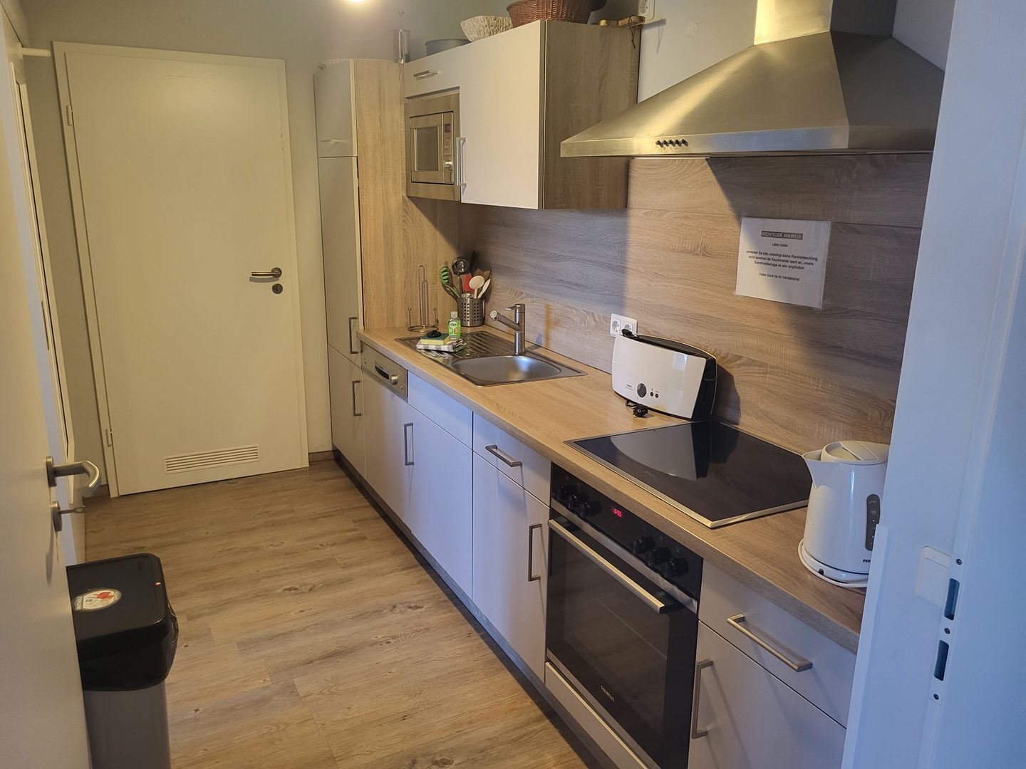 A modern kitchen with a microwave, oven, and a coffee maker.