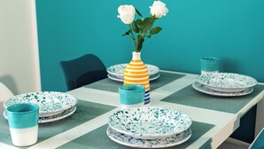 Una mesa de comedor dispuesta con platos, tazas y un florero con flores.