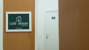 Un cartel enmarcado con el texto 'Colê House apartments' e información de contacto.