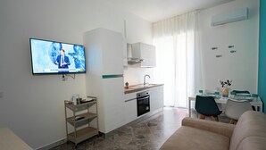 Una cocina moderna con horno integrado, un comedor con mesa y sillas, y una sala de estar con sofá.