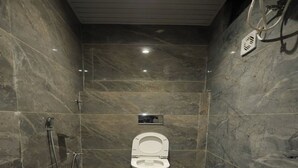 A small, modern bathroom with a toilet, a shower, and a mirror. - Aayu Residency (Vikasnagar)