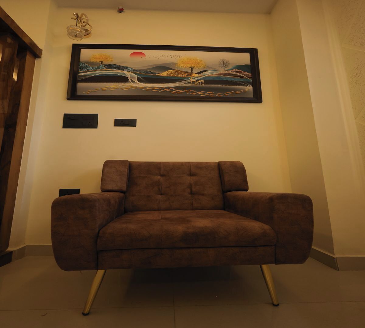 En brun lænestol med træben i et rum med et billede på væggen.