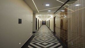 A modern hotel hallway with geometric patterned flooring, recessed lighting, and mirrored walls. - Aayu Residency (Vikasnagar)