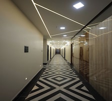 En moderne hotelgang med geometrisk gulvbelægning, indbygget belysning og spejlvægge.