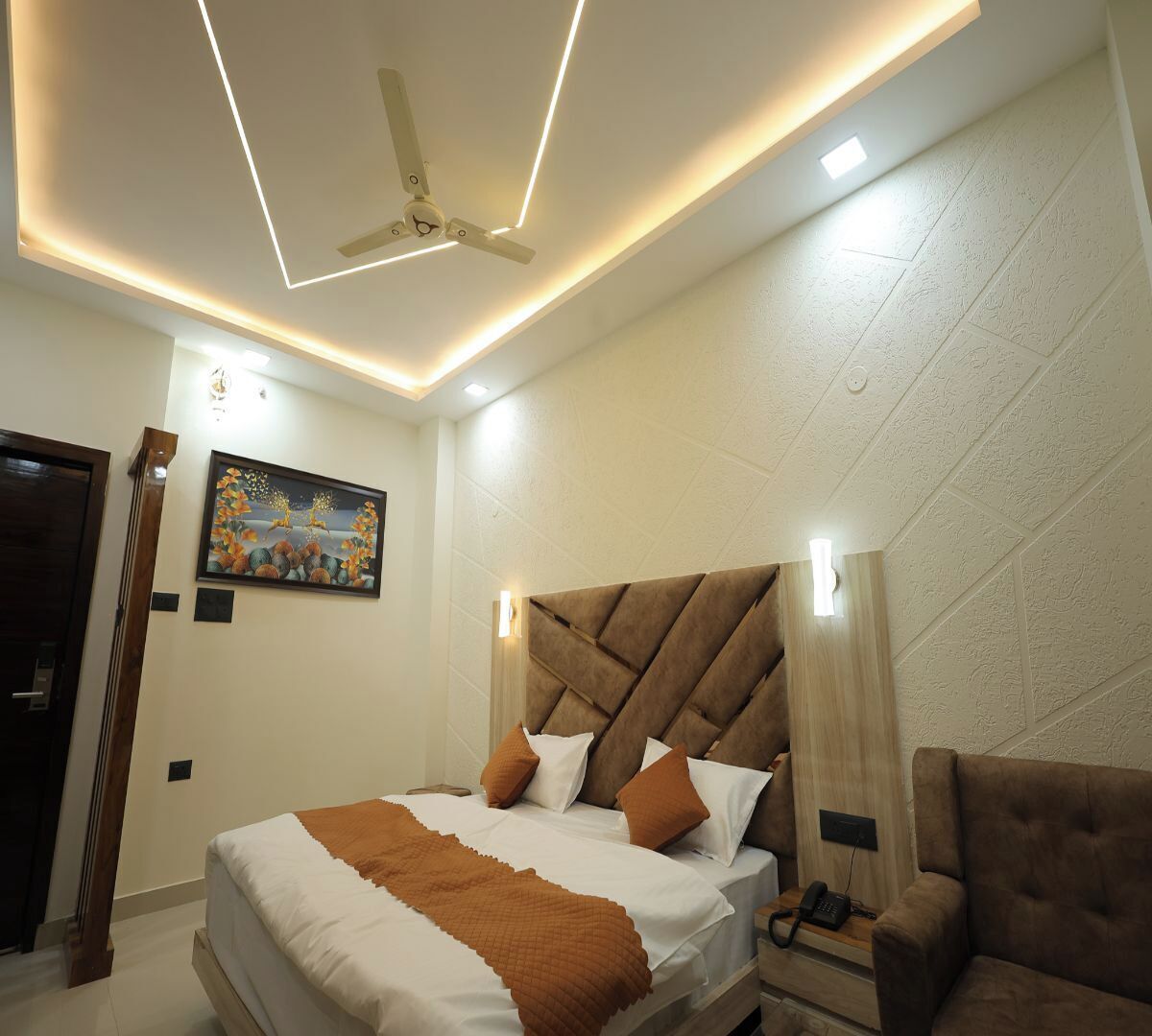 Un dormitorio moderno con una cama grande, ventilador de techo, iluminación empotrada y un cuadro en la pared.
