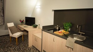 A compact kitchen with a dining area, a flat-screen TV, and a small dining table.
