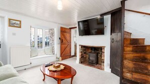 A living room with a fireplace, a television mounted above it, a sofa, and a coffee table.