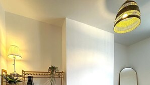 A room with a wooden shelving unit, a lamp, a mirror, and a hanging light fixture. - Wigan 1BR Haven:  Perfect for a Relaxing Stay (Wigan)