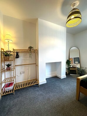 A room with a wooden shelving unit, a lamp, a mirror, and a hanging light fixture.