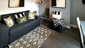 Een moderne woonkamer met een bank, een kamerbreed tapijt, een eettafel en twee kunstwerken aan de muur.
