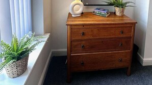 Een houten dressoir met een spiegel, een lamp en twee planten in potten.