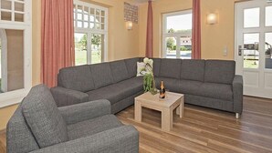 Un salón con un sofá seccional gris, una pequeña mesa de centro de madera y una planta en maceta.