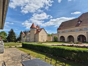Une cour avec un bâtiment qui ressemble à un château, une zone pavée et une table entourée de chaises.