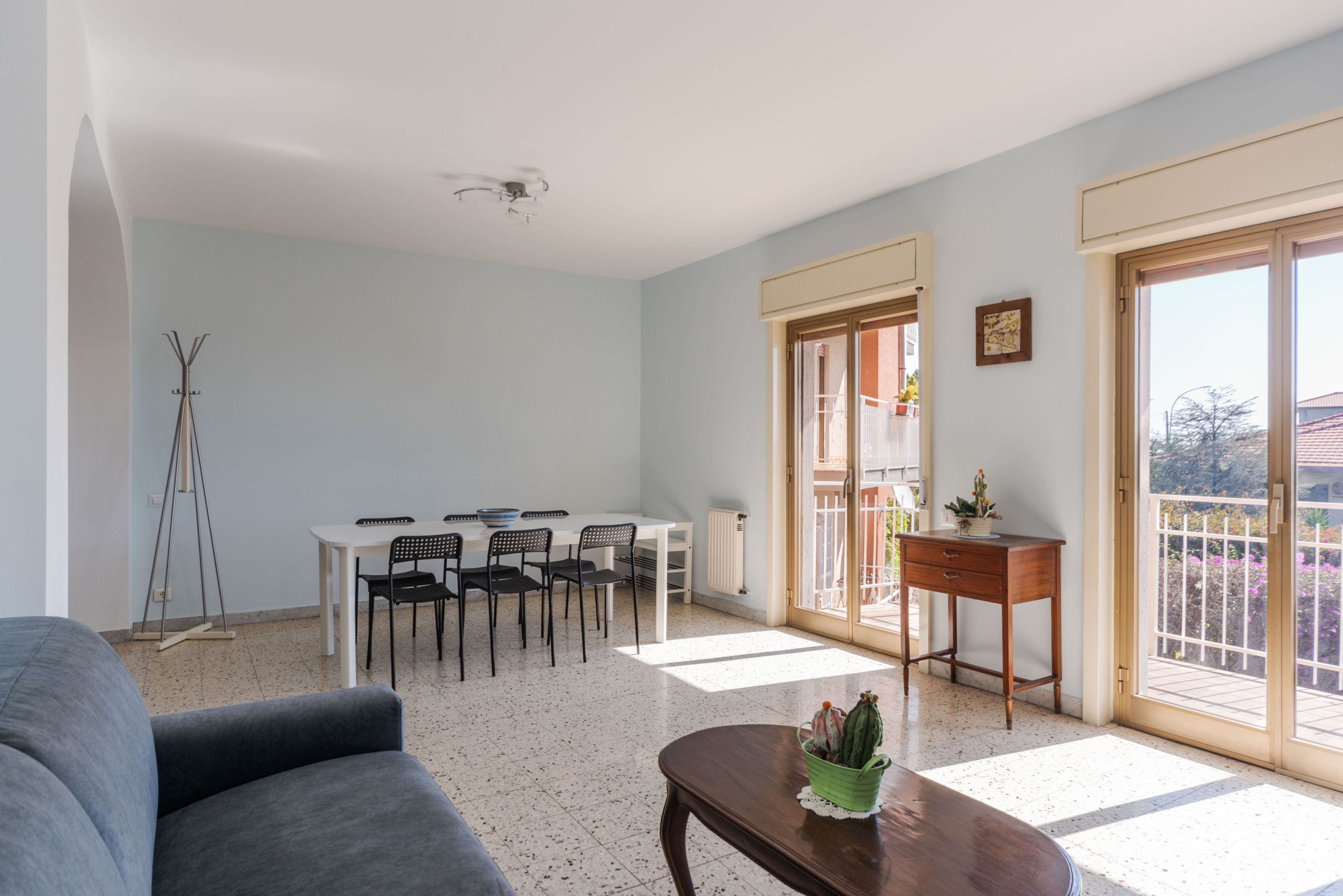 Un salón espacioso con una mesa de comedor, sillas, un sofá y una mesita con una planta.