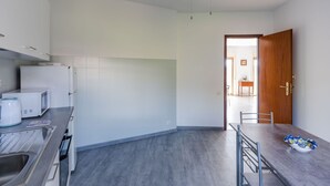 Une cuisine moderne avec des meubles blancs, un four à micro-ondes, une bouilloire et un coin repas comprenant une table et des chaises.