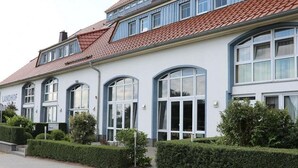 A two-story building with a red-tiled roof and white walls. The name "LANDHOF" is visible on the facade.