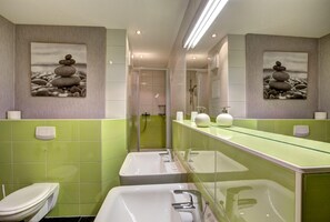 A modern bathroom with green tiled walls, a glass shower enclosure, and two sinks with white fixtures. - Windflüchter LH-305 - The country farm Windflüchter LH-305 - Family-friendly (Stolpe auf Usedom)