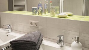 Une salle de bain avec un lavabo, un miroir et des articles de toilette posés sur le comptoir.