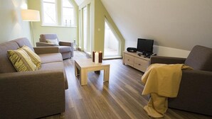 Un salon moderne avec un canapé, des fauteuils, une table basse et un téléviseur.
