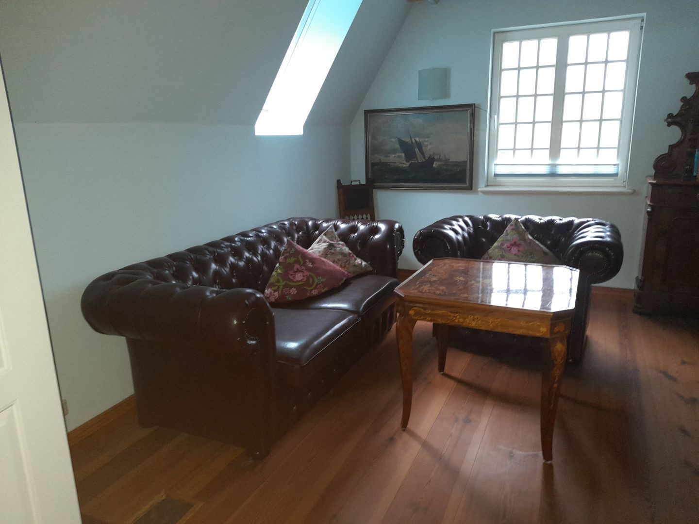 A living room with a dark brown leather sofa, a wooden coffee table, and a window with blinds.
