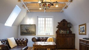 Una sala de estar acogedora con un sofá de cuero, una mesa de centro de madera, una estantería y un ventanal con vistas.