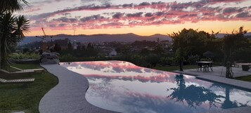 Una piscina de borde curvo, rodeada por un área pavimentada con bancos.