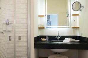 A bathroom with a glass shower enclosure, a black countertop sink with a mirror above, and a window with a view of a brick building. - Lexington RE-03 - The Lexington coach house RE-03 Holiday apartment with terrace on (Stolpe auf Usedom)