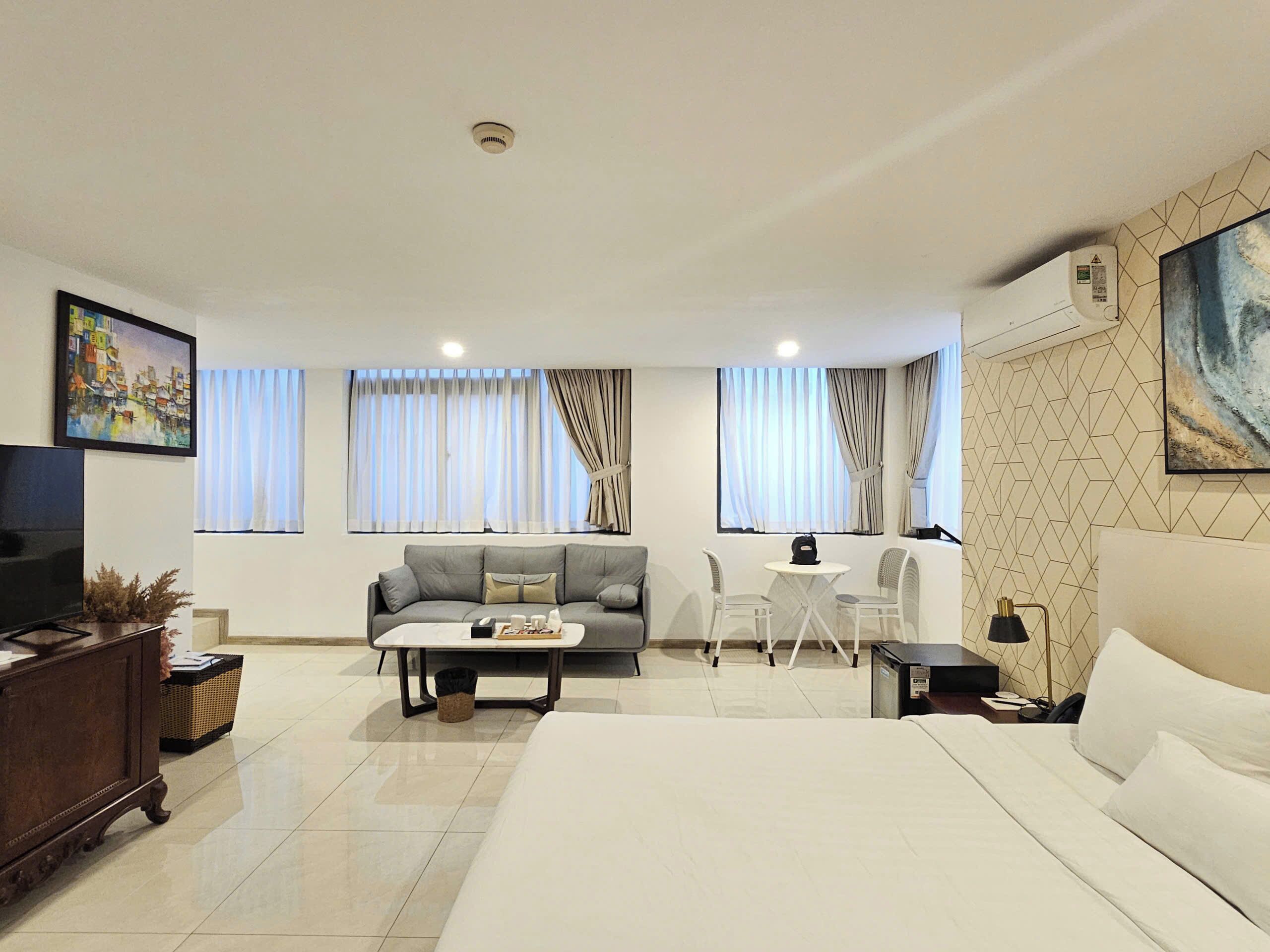 A modern hotel room with a bed, a sofa, a small table, and a TV.